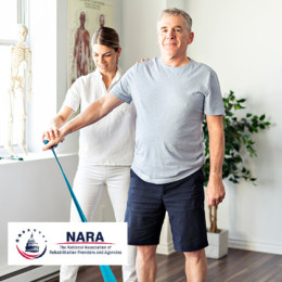 Physical Therapist standing behind patient and assisting in arm band exercise 