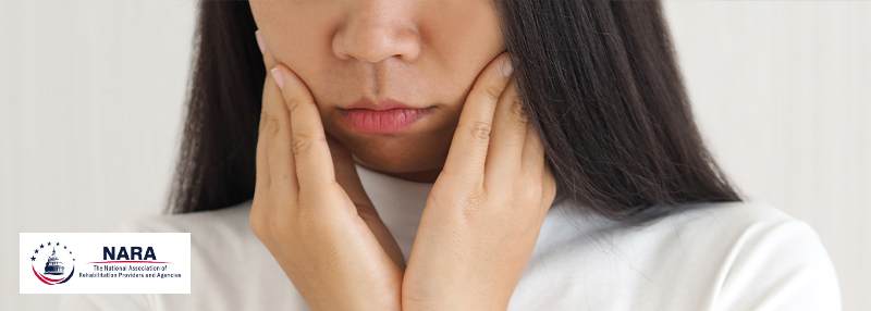 Woman holding her hands to either side of her jaw, looking uncomfortable