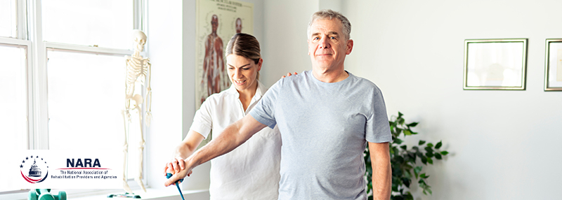 Physical Therapist standing behind patient and assisting in arm band exercise 