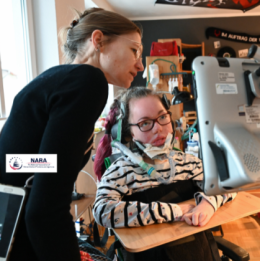 Person with spinal muscular atrophy looking at screen with caregiver