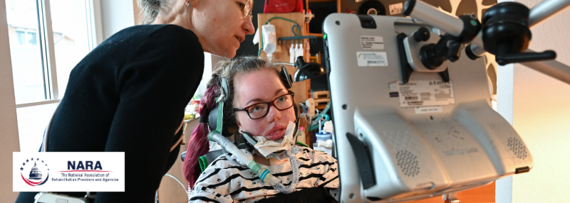 Person with spinal muscular atrophy looking at screen with caregiver