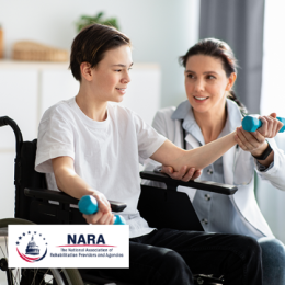 Physical therapist working with younger male in wheelchair to curl weights