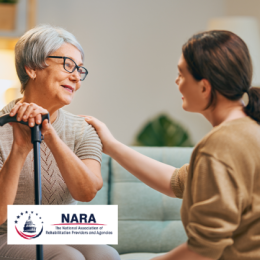 Younger woman smiling at older woman who is smiling back and has her hands on a cane