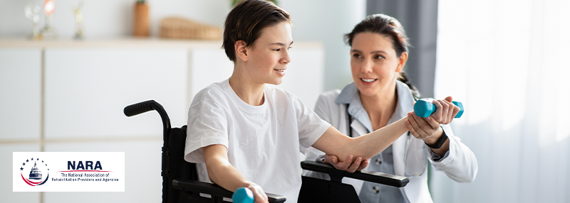 Physical therapist working with younger male in wheelchair to curl weights